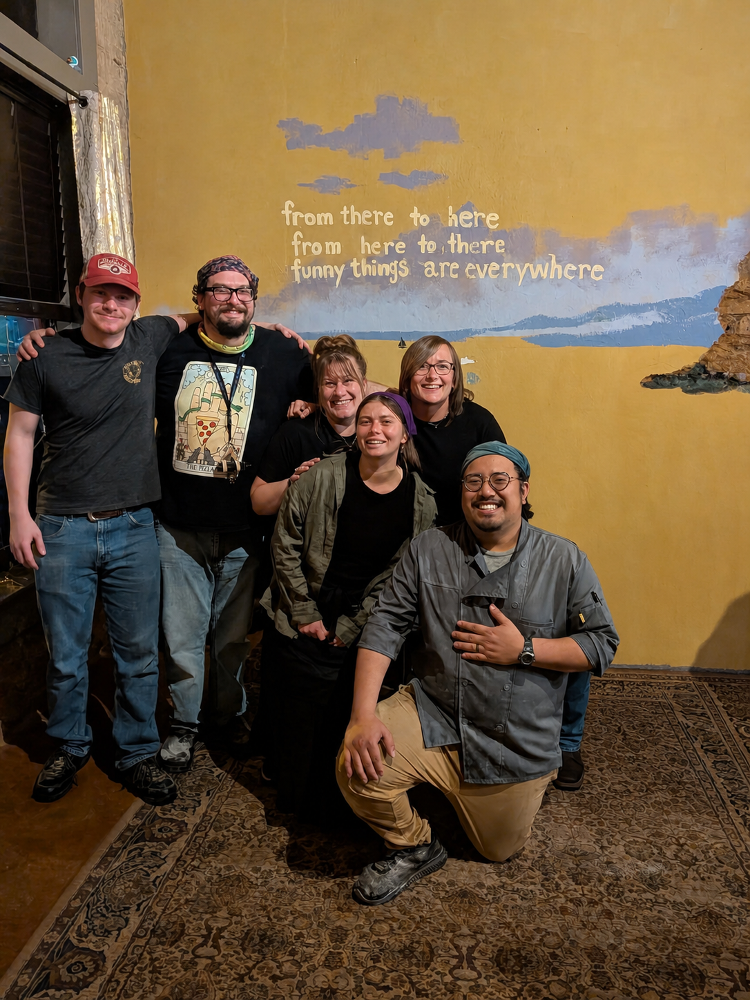 The Blue Duck team beneath the restaurant's playful wall quote.